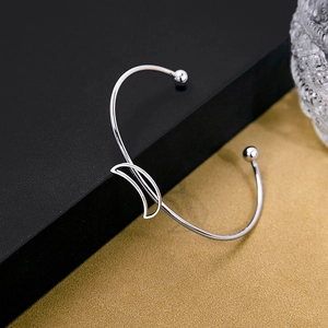 Close-up of silver minimalist open bangle with crescent moon and bead details
