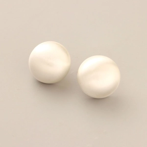 Detail view of round cream pearl stud earrings with a smooth brushed matte texture