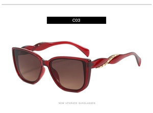 Macro detail of oversized red sunglasses featuring twisted gold metal temple accents