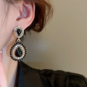 Close-up of model wearing dark vintage teardrop earrings with crystals and gold finish