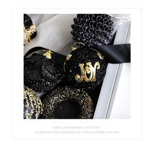 Detail of elegant black and gold Christmas ornaments with JOY patch and beaded texture
