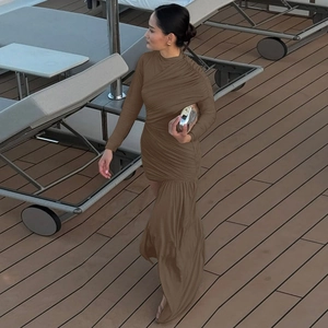 Detail of ruched brown knit dress featuring a turtleneck and asymmetric hem on a wooden deck