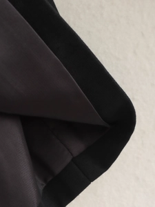 Détail rapproché du bord côte noir et de la doublure en sergé marron foncé de la veste