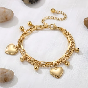 Detail of golden double-layer heart bracelet with beads, lobster clasp and extension chain