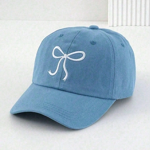 Detailed view of white bow embroidery on light blue cotton canvas baseball cap texture