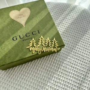 Golden Merry Christmas cake topper with tree designs on a luxury green gift box