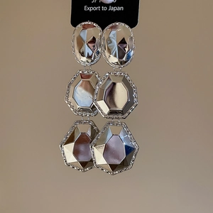 Vue détaillée de boucles d'oreilles géométriques argentées aux facettes polies