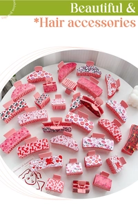 Flat lay of pink heart-themed acrylic hair claws with LOVE and kiss patterns