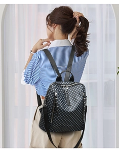 Detailed back view of a black and white checkerboard backpack on a female model