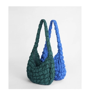 Detailed close-up of quilted cloud bag stitching texture and zipper in dark green and royal blue