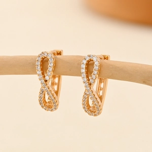 Macro detail van champagne gouden infinity oorbellen met micro-pave witte zirkonia's