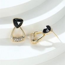 Detail of gold tassel earrings with black triangular gem and pavé crystal setting