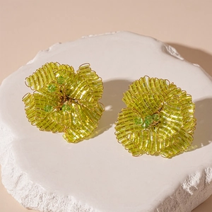 Dettaglio di orecchini a fiore con perline di vetro verdi fatti a mano e filo dorato
