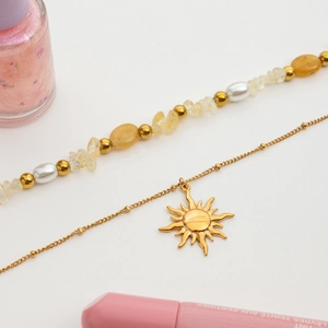 Detail of double-layered necklace with sun pendant, citrine beads and pearls