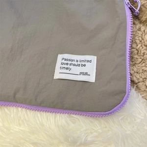 Detail of grey waterproof storage bag with purple zipper and white fabric label