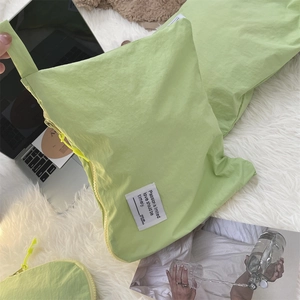 Detail view of light green waterproof travel storage bag on white plush background