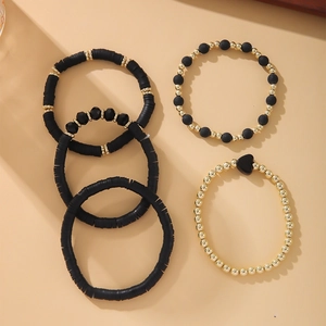 Close-up of 5-piece black and gold bohemian bracelet set featuring clay discs and heart charm