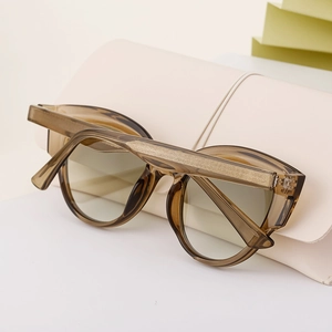 Detailed shot of amber cat-eye sunglasses resting on a beige pouch with soft warm lighting