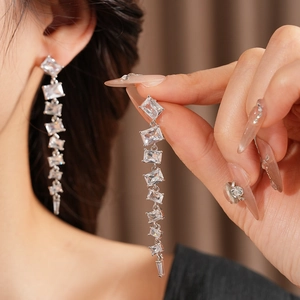 Macro view of long silver tassel earrings with rectangular cubic zirconia stones