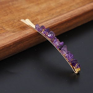 Golden hair clip featuring purple natural crystal stone chips on a wooden tray