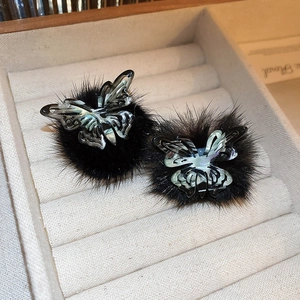 Macro view of black flocked heart earrings with rhinestone butterflies and silver needles