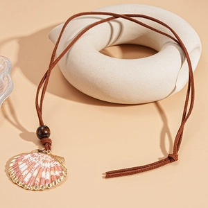 Detail showing natural scallop shell pendant with gold edges and braided brown cord