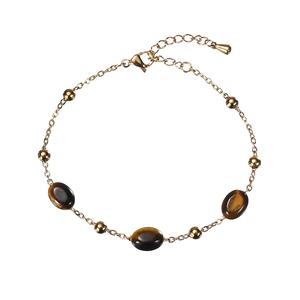 Gold stainless steel bracelet with tiger eye stones and beads on white background