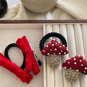 Detail of red mushroom hair ties and bow clip set with elegant pearl accents