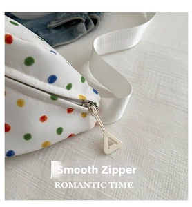 Detailed close-up of smooth white metal zipper on a colorful polka dot crossbody bag