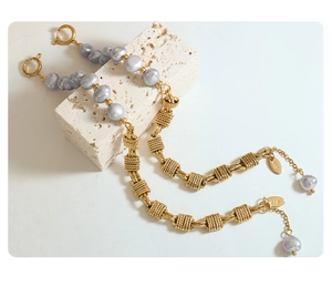 Macro detail of brass chain bracelet with gray baroque pearls on a textured stone