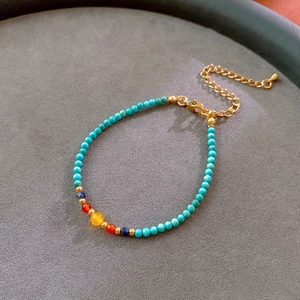 Detail of colorful beaded bracelet with gold metal clasp on grey velvet background