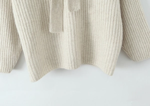 Nahaufnahme von cremefarbenem Strickpullover mit hochwertiger Rippstruktur und weichem Stoff