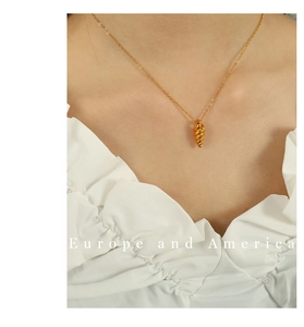 Detailed view of a gold conch shell pendant necklace worn on a woman's neckline