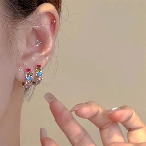 Close-up of rainbow zircon huggie hoops and stud earrings set on ear lobe