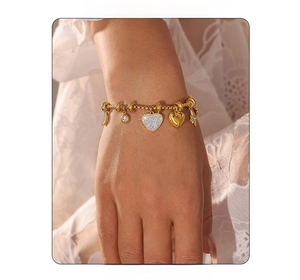 Detail of gold-plated 18k bracelet featuring sparkling heart and celestial star moon charms