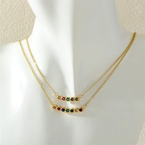 Detail showing a double-layered gold necklace with vibrant multi-color rainbow gemstones