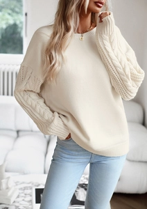 Dettaglio del maglione beige in maglia con maniche raglan e motivi a treccia fitta