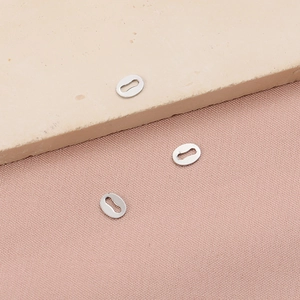 Three silver stainless steel oval connector tags for DIY jewelry making on stone background
