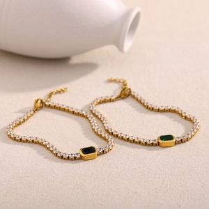 Detail view of 18K gold plated tennis bracelets featuring black and green emerald-cut stones