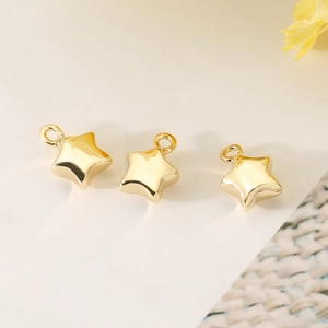 Macro detail of three glossy gold star pendants with polished finish for DIY jewelry