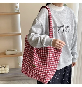 Detail of red and white houndstooth wool tote bag with golden metal plaque on strap
