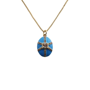 Gros plan sur le collier doré avec pendentif œuf en émail bleu et pierres de zircon colorées