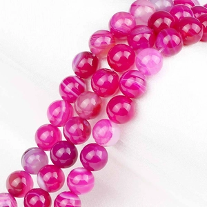 Macro shot of polished pink striped agate round beads with natural white patterns