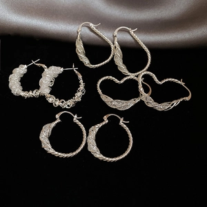 Detailed view of silver hoop earrings featuring intricate woven and twisted metal textures