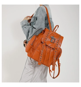 Side view of orange soft leather backpack with silver rivets and cross pendant detail