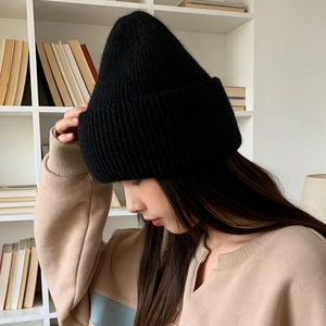 Close-up of thick black knitted beanie showing soft plush rabbit fur texture on a model
