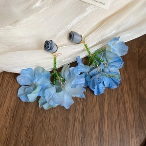 Close-up of blue mesh flower earrings with grey rose buds and green beaded stems