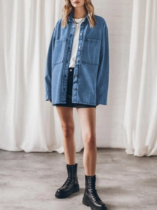 Full body view of women's oversized blue denim shirt jacket with large pockets and long sleeves