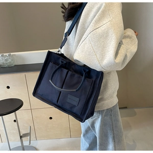 Dettaglio borsa tote in tela blu navy con doppie tasche frontali e tracolla regolabile