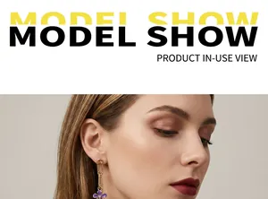 Close-up of gold paperclip link earrings with faceted purple pendant on a female model